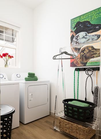 A laundry room with a basket on the floor and a washing machine and dryer in the background.